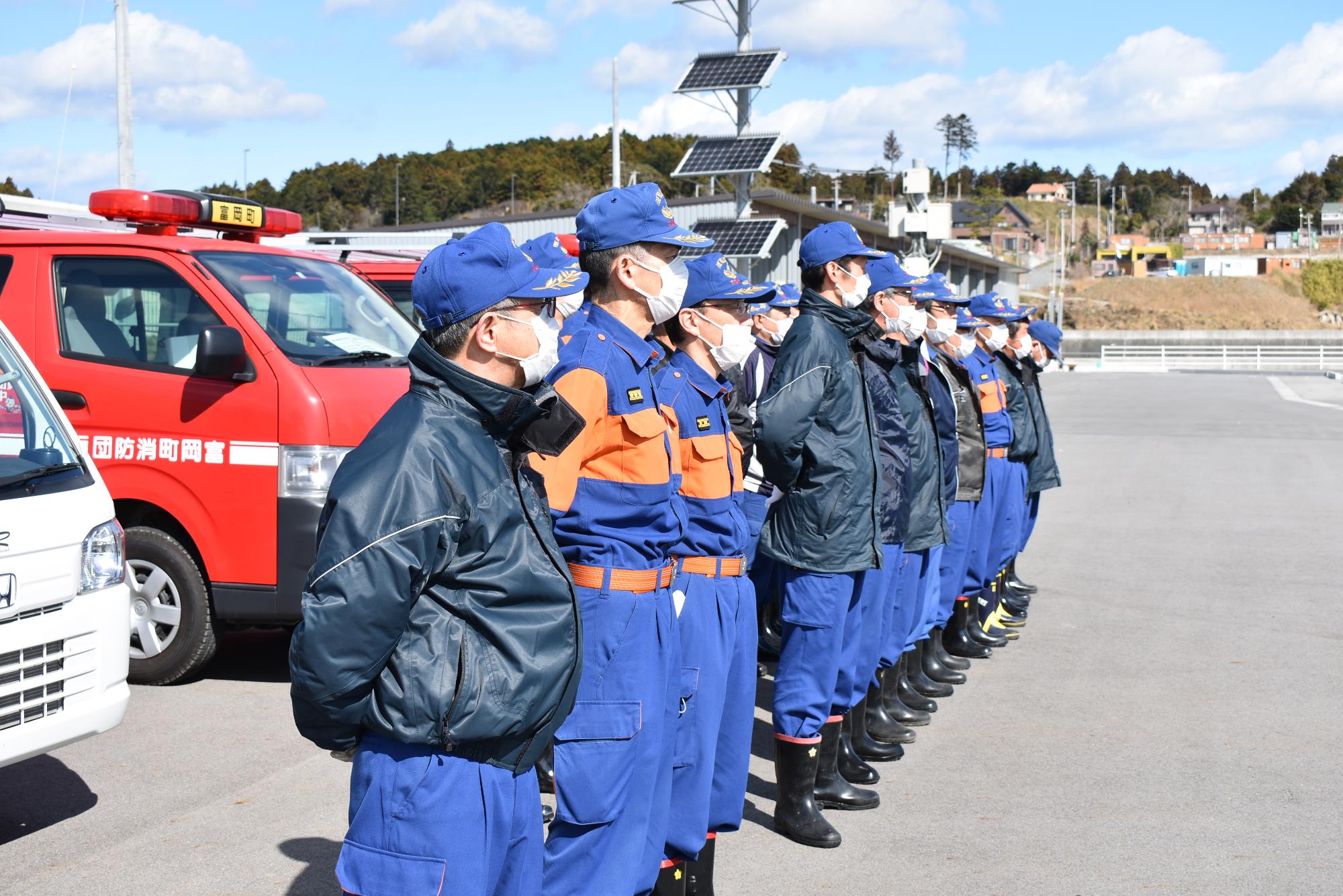 富岡漁港の漁具倉庫まえに整列する団員