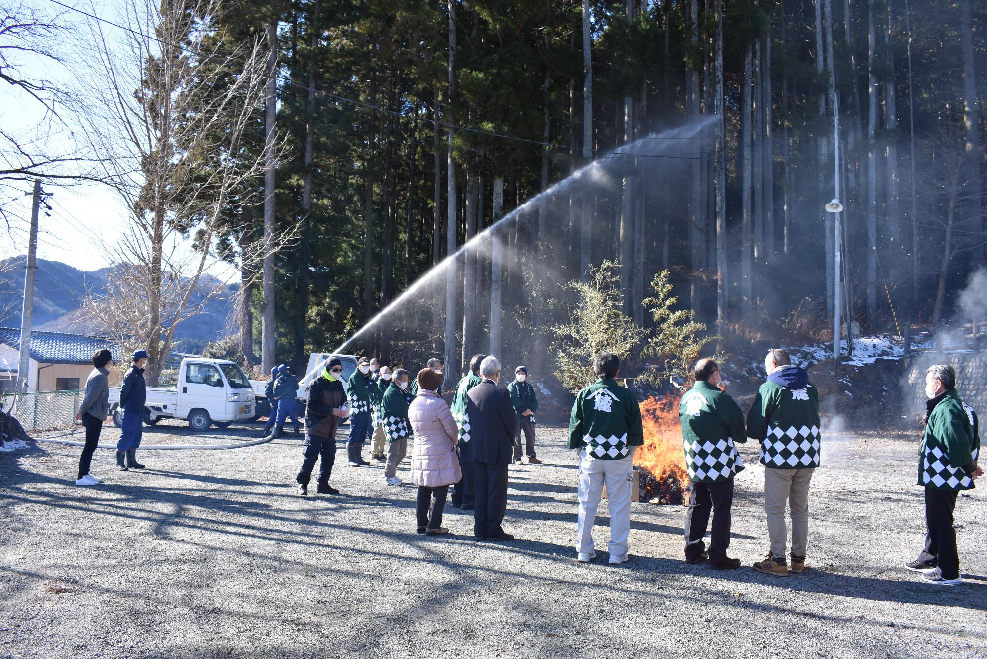 麓山神社境内で焚かれたどんと祭の火により山林へ延焼しないよう放水する消防団員