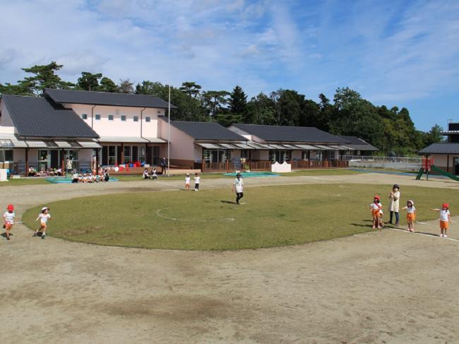 富岡町立にこにここども園　建物外観と遊ぶ園児