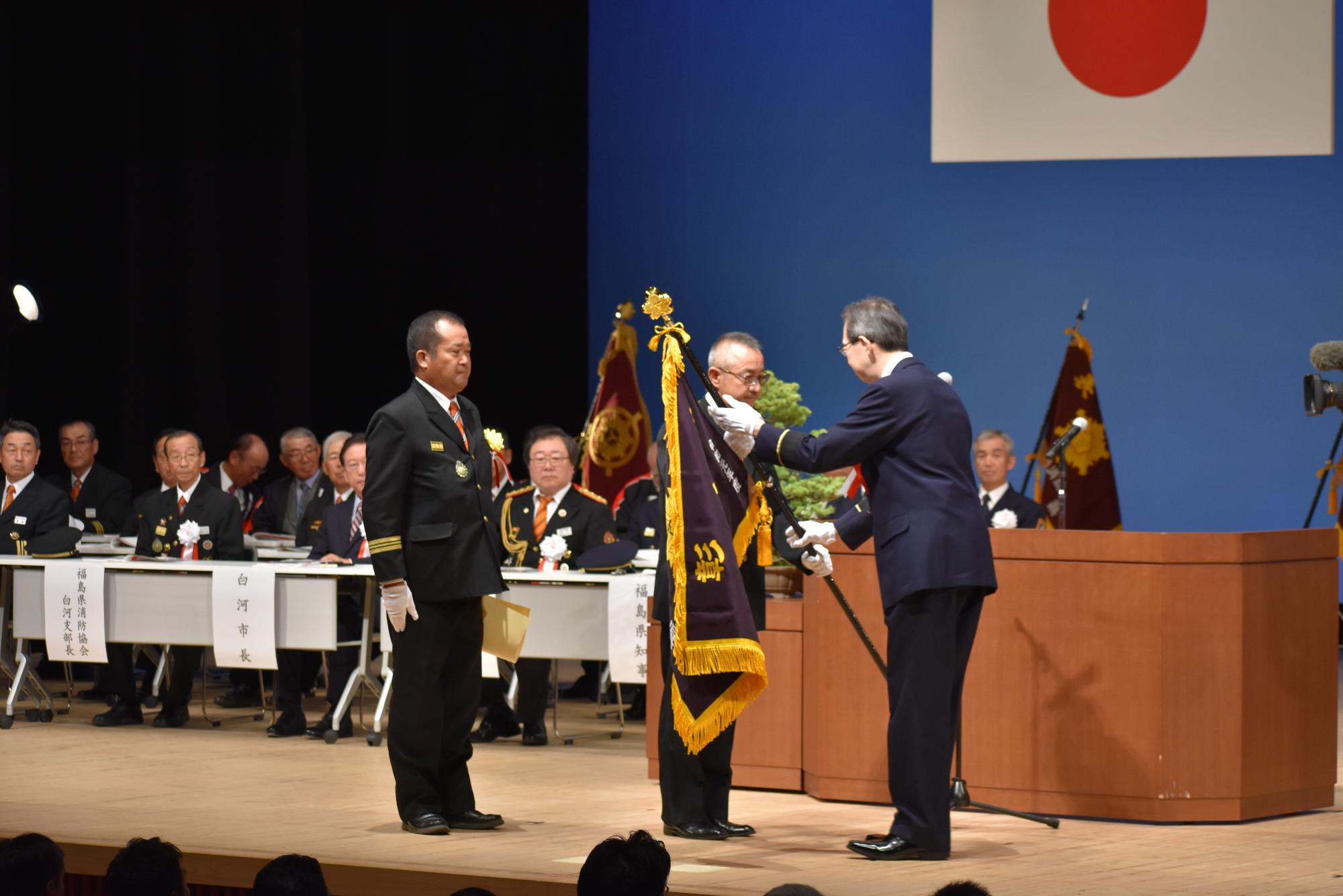 消防大会で内堀雅雄福島県知事から表彰旗を授与される林副団長