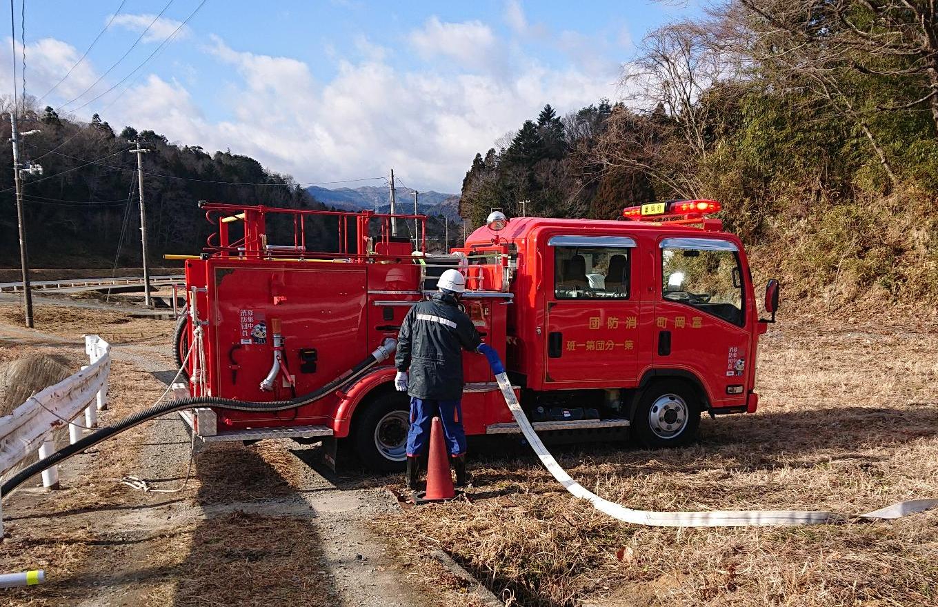 付近の河川から揚水する団員とポンプ自動車