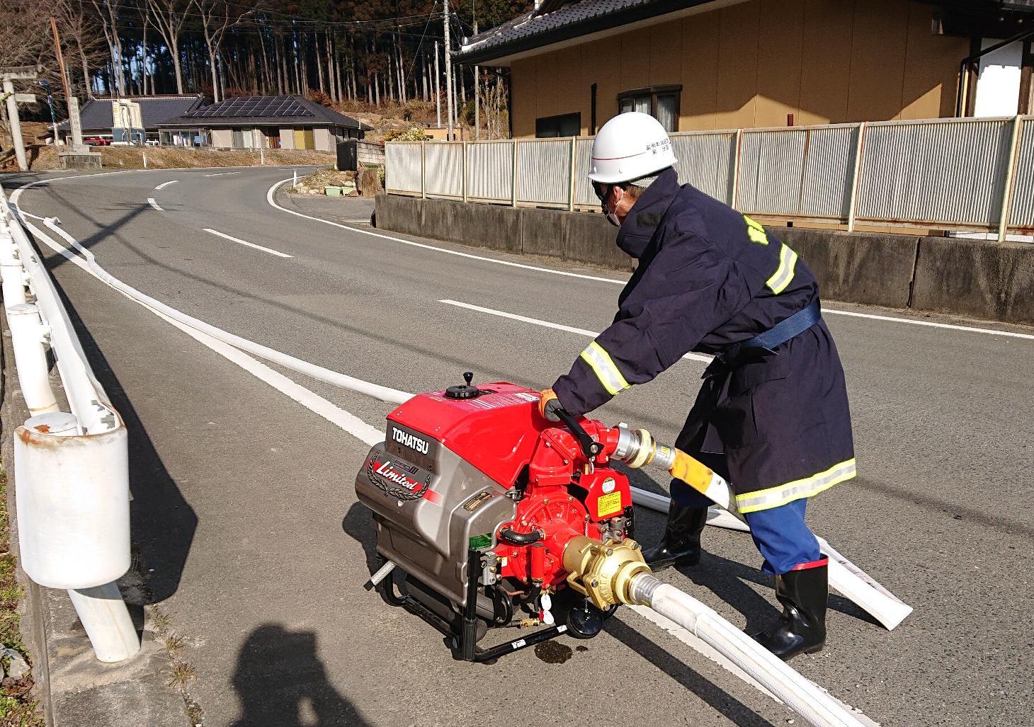 消火栓からの水を小型ポンプで加圧し、送水する団員。